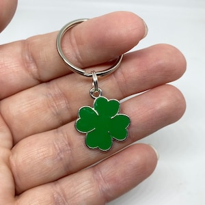 May include: A silver key ring with a green four-leaf clover charm.