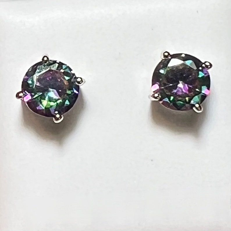 Pu&ograve; includere: Un paio di orecchini a perno d'argento con pietre preziose rotonde e iridescenti. Le pietre preziose presentano un arcobaleno di colori, tra cui verde, blu, viola e rosa.