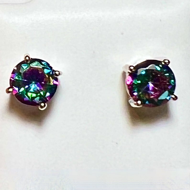 Pu&ograve; includere: Un paio di orecchini a perno d'argento con pietre rotonde iridescenti. Le pietre preziose presentano un arcobaleno di colori, tra cui viola, verde, blu e rosa.