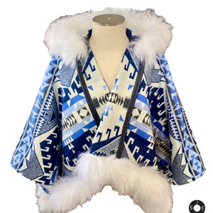 May include: A blue and white patterned hooded poncho with a white fur trim. The poncho has a geometric design and is made of a soft, warm fabric.