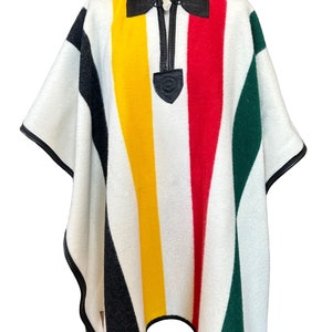 May include: A hooded poncho with vertical stripes in black, yellow, red, and green on a white background. The poncho has black leather trim and a black leather zipper pull. The garment is displayed on a mannequin.