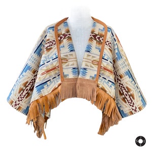 May include: A brown and blue patterned poncho with fringe trim and leather accents. The poncho is made of a soft, woven fabric and has a V-neck.