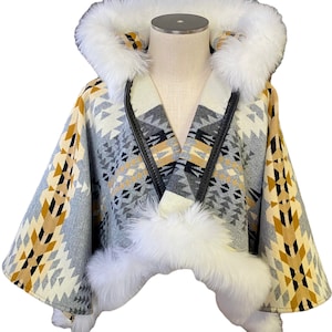 May include: A gray and white hooded poncho with a geometric pattern and white fur trim. The poncho has a leather zipper and a white fur hood.