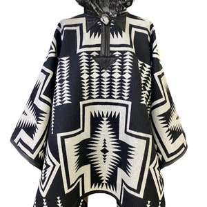 Könnte beinhalten: Schwarz-weißer Kapuzenponcho mit geometrischem Muster. Der Poncho hat einen Reißverschluss und einen Lederbesatz.
