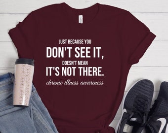 May include: A maroon t-shirt with white text that reads "JUST BECAUSE YOU DON'T SEE IT, DOESN'T MEAN IT'S NOT THERE. chronic illness awareness".