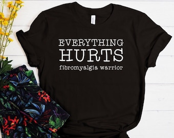 May include: Black t-shirt with white text that reads "Everything Hurts fibromyalgia warrior".