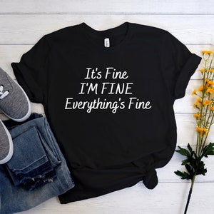 May include: Black t-shirt with white text that reads "It's Fine I'M FINE Everything's Fine".