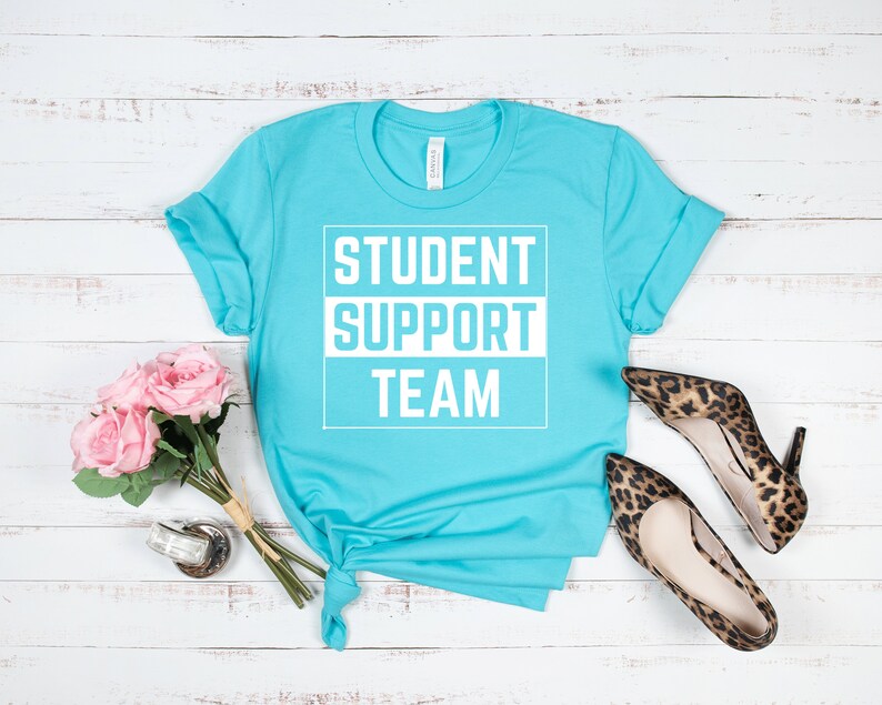 Może przedstawiać: Turkusowa koszulka z nadrukiem "STUDENT SUPPORT TEAM" w kolorze białym.