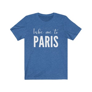 May include: A heathered blue short-sleeve t-shirt featuring the white printed text Take me to PARIS. The design includes the words Take me to in a cursive script font above the word PARIS in a bold, uppercase, sans-serif typeface.