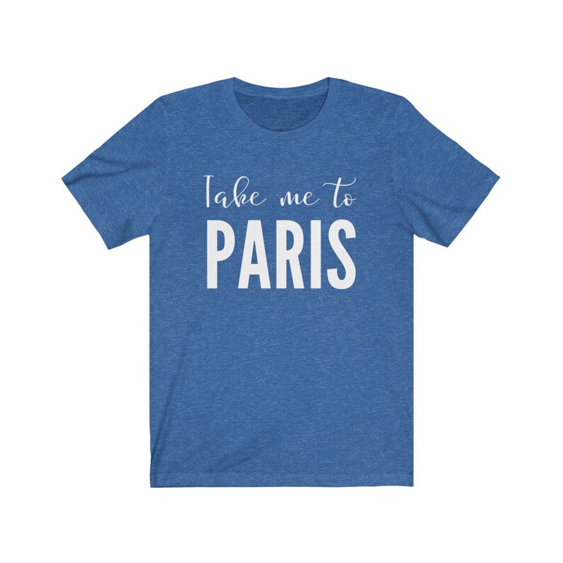 May include: A heathered blue short-sleeve t-shirt featuring the white printed text Take me to PARIS. The design includes the words Take me to in a cursive script font above the word PARIS in a bold, uppercase, sans-serif typeface.