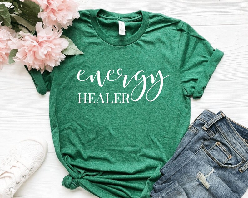Pode incluir: Camiseta verde com texto branco que diz "energy healer" em fonte cursiva.