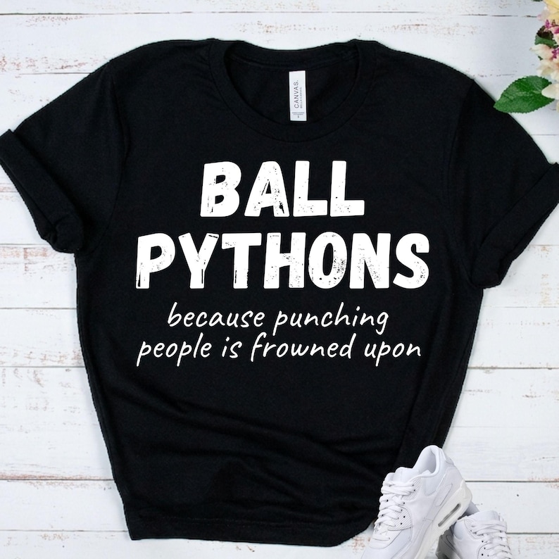 May include: Black t-shirt with the words "BALL PYTHONS" in large white letters. Below, in a smaller font, it reads "because punching people is frowned upon."