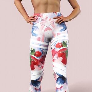 May include: White leggings with a colorful watercolor print of strawberries and abstract shapes.
