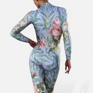 May include: A full-body jumpsuit with a floral design of pink roses and green foliage on a pale blue backdrop. The long-sleeved garment has a high neckline and a close fit, displaying the botanical print.