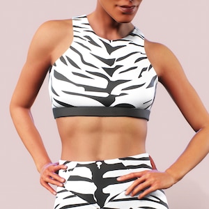 Könnte beinhalten: Ein Sport-Set aus schwarzem und weißem Zebra-Muster-Sport-BH und Leggings. Das Oberteil hat einen Racerback-Stil und die Leggings haben einen hohen Bund.