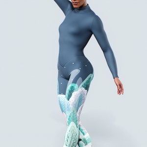 Può includere: Un body intero blu-grigio. I leggings presentano un design fantasioso e colorato con elementi botanici azzurri, verdi e rosa. Il top a maniche lunghe ha uno scollo alto.