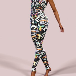 May include: A black jumpsuit with a colourful cassette tape print. The jumpsuit has a sleeveless design and a high neckline.