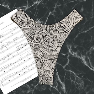 May include: Black and white patterned underwear with a musical theme. The pattern includes musical notes, piano keys, and other musical symbols.