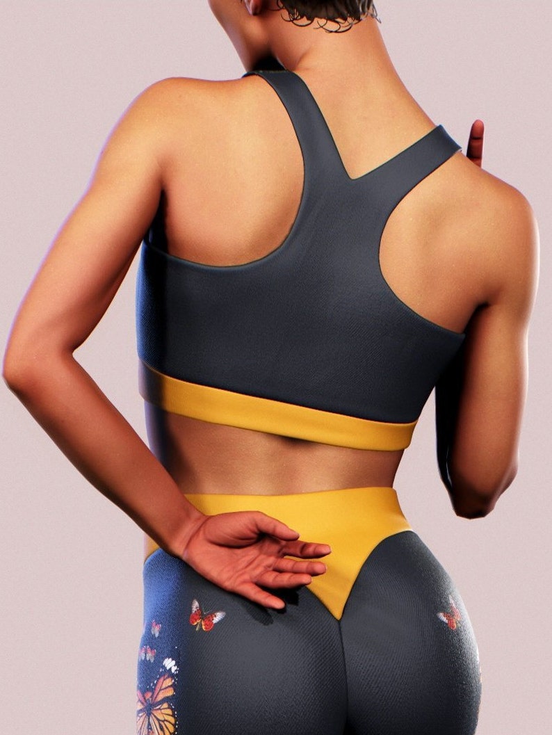 May include: A dark blue and yellow sports bra and leggings set with a butterfly print. The leggings have a yellow waistband and a V-shaped yellow panel at the back.