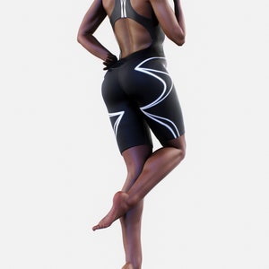 May include: A black and white athletic bodysuit with a high neckline and a cutout back. The bodysuit has a geometric design on the legs.