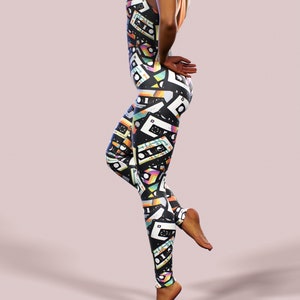 May include: Black leggings with a colourful pattern of cassette tapes. The leggings are form-fitting and have a high waist.