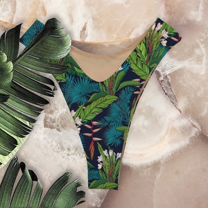 May include: A black and blue bikini bottom with a tropical print featuring green leaves, white flowers, and red accents.