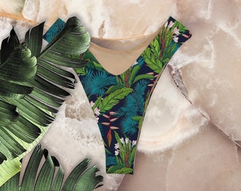 May include: A black and blue bikini bottom with a tropical print featuring green leaves, white flowers, and red accents.