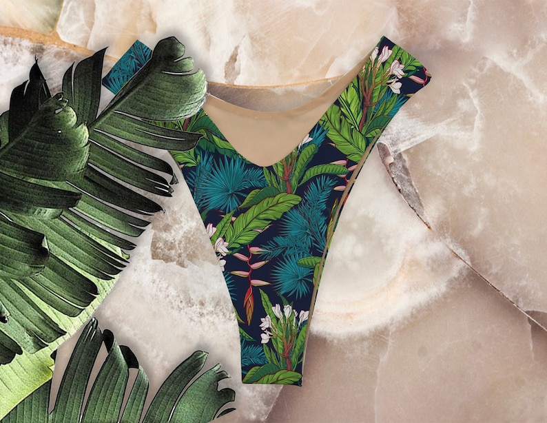 May include: A black and blue bikini bottom with a tropical print featuring green leaves, white flowers, and red accents.