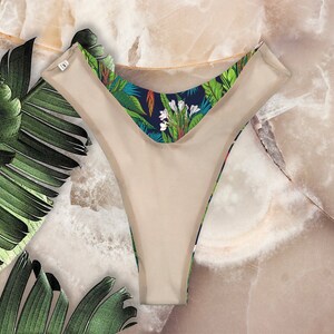 May include: Beige underwear with a tropical print on the waistband. The print features green leaves, white flowers, and blue accents.