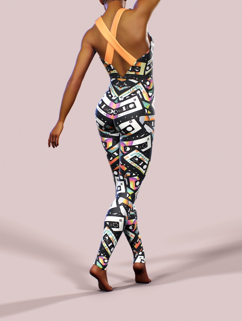 May include: Black one-piece jumpsuit with a colourful cassette tape pattern. The jumpsuit has a criss-cross strap design at the back.