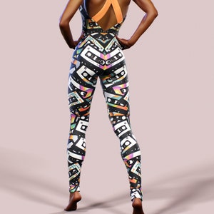 May include: Black and white leggings with a colourful cassette tape pattern. The leggings have a criss-cross strap back design.