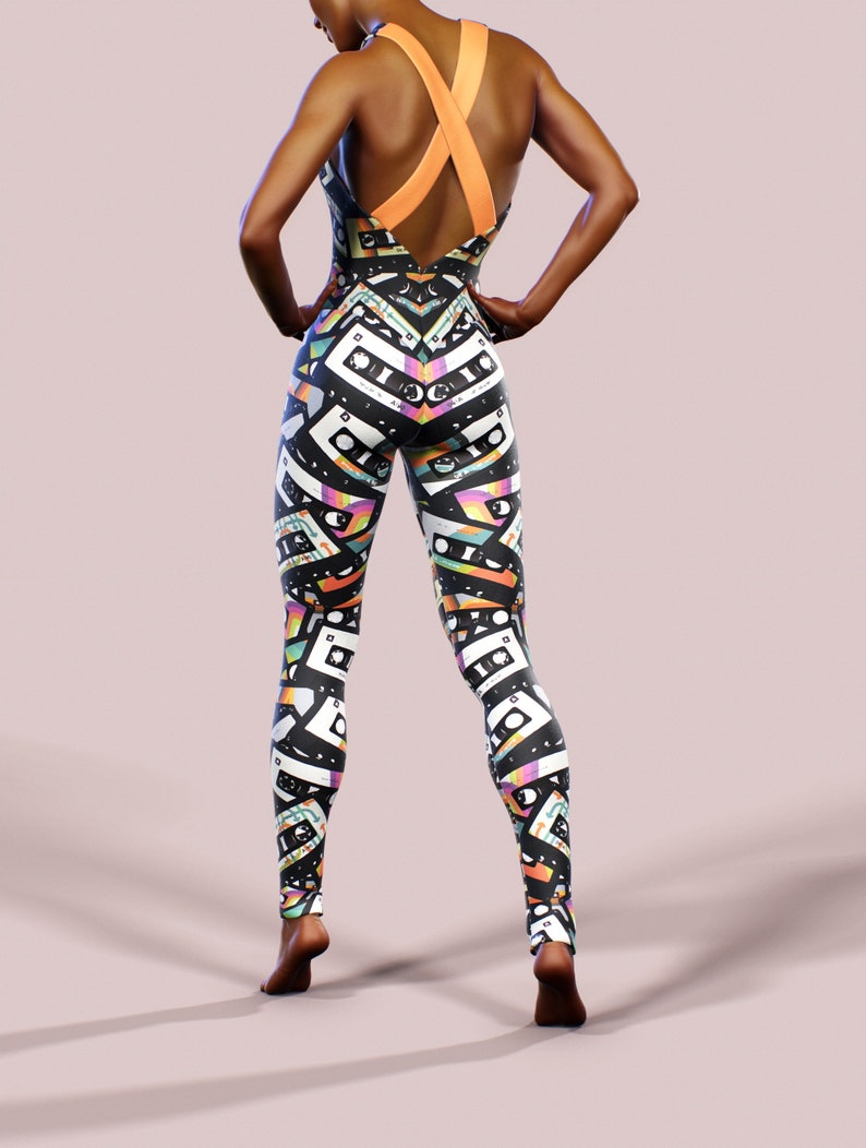 May include: Black and white leggings with a colourful cassette tape pattern. The leggings have a criss-cross strap back design.