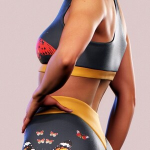 May include: A dark blue sports bra with a yellow band and a red butterfly print. Matching dark blue leggings with a yellow waistband and a large butterfly print in orange, yellow, and black.