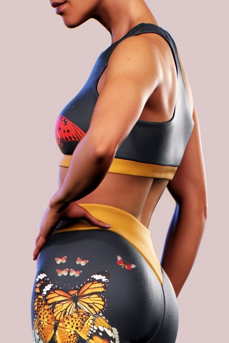 May include: A dark blue sports bra with a yellow band and a red butterfly print. Matching dark blue leggings with a yellow waistband and a large butterfly print in orange, yellow, and black.