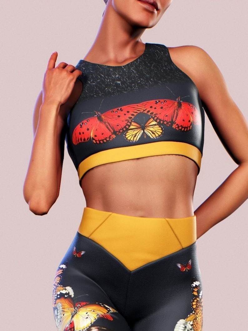 May include: Black and yellow athletic leggings with a butterfly print. The leggings have a high waist and a yellow waistband. The butterflies are red, orange, and yellow.