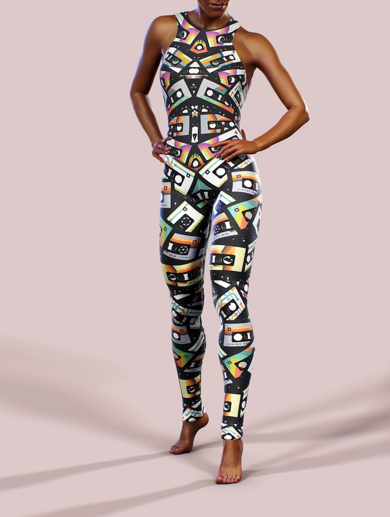 May include: A black jumpsuit with a colourful cassette tape pattern. The jumpsuit has a high neckline and sleeveless design.