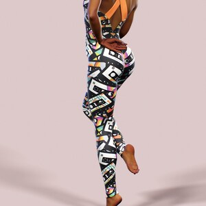 May include: Black and white jumpsuit with a colourful cassette tape pattern. The jumpsuit has a criss-cross back strap and a scoop neck.