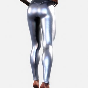 May include: High-waisted leggings in a metallic silver finish with a smooth, reflective surface. The leggings feature a fitted silhouette that extends to the ankles, showcasing a seamless design with a central seam detail along the back.