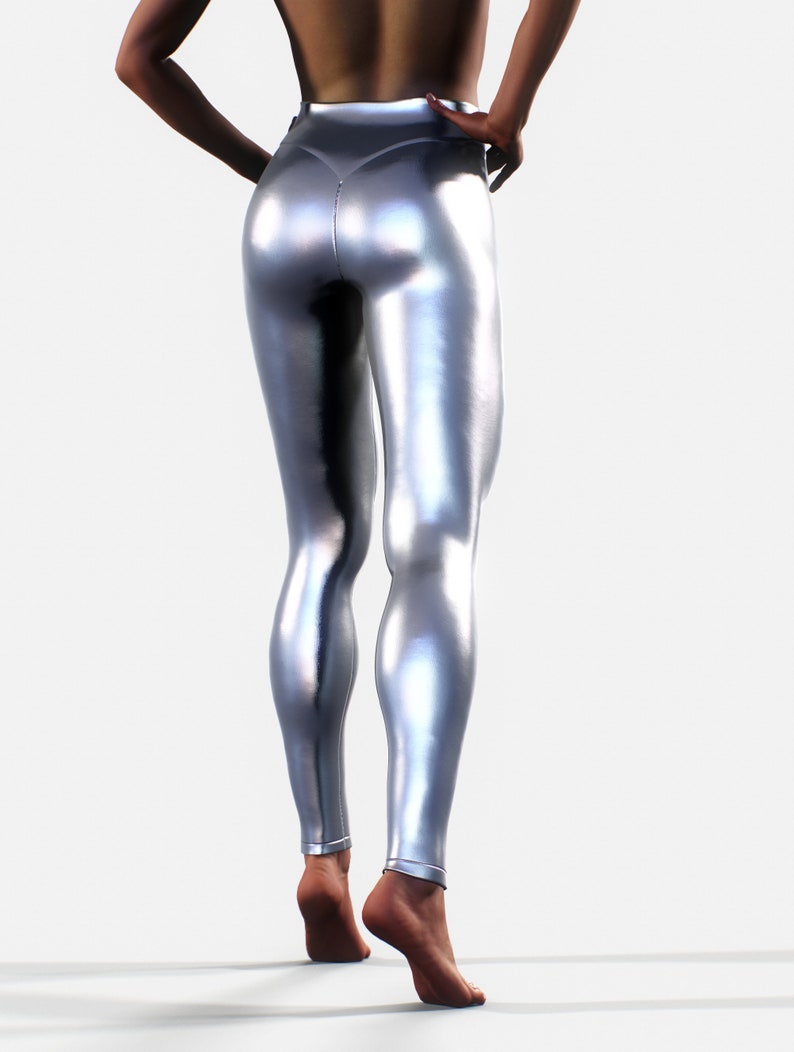 May include: High-waisted leggings in a metallic silver finish with a smooth, reflective surface. The leggings feature a fitted silhouette that extends to the ankles, showcasing a seamless design with a central seam detail along the back.