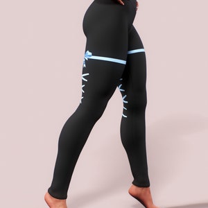 Pu&ograve; includere: Leggings neri con nastro azzurro e design con lacci. I leggings presentano una vita alta e una silhouette aderente. Un nastro azzurro &egrave; legato a fiocco sulla coscia, con dettagli di lacci bianchi. I leggings sono realizzati in un materiale morbido ed elastico.