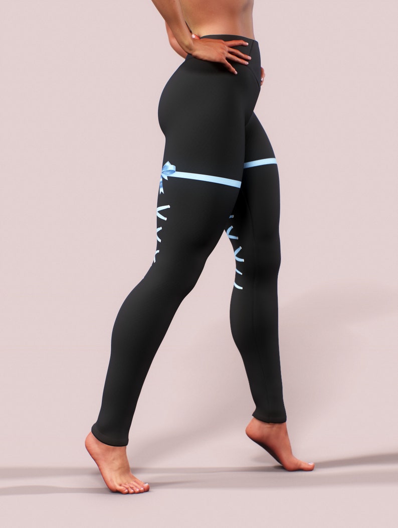 Pu&ograve; includere: Leggings neri con nastro azzurro e design con lacci. I leggings presentano una vita alta e una silhouette aderente. Un nastro azzurro &egrave; legato a fiocco sulla coscia, con dettagli di lacci bianchi. I leggings sono realizzati in un materiale morbido ed elastico.