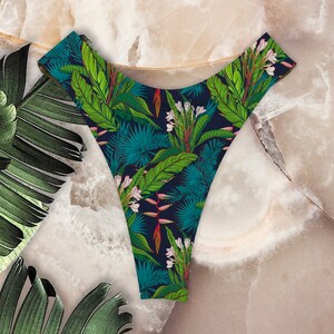 May include: Black underwear with a tropical leaf and flower print. The print features green leaves, white flowers, and pink accents.