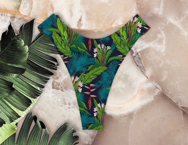 May include: Black underwear with a tropical leaf and flower print. The print features green leaves, white flowers, and pink accents.