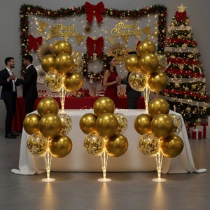 May include: Gold balloons and confetti balloons on illuminated stands, arranged for a festive event. The background includes a Christmas tree, decorative lights, and a table with a red tablecloth. The words "Merry Christmas" are displayed.