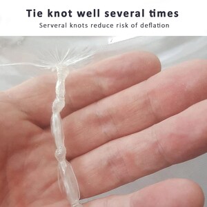 May include: Close-up of a clear plastic tie knotted several times. The text "Tie knot well several times" and "Serveral knots reduce risk of deflation" is visible above the knot.