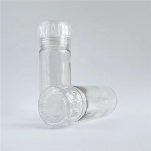 Puede incluir: Dos tarros de especias de vidrio transparente con tapas de plástico transparente. Las tapas tienen un diseño texturizado y un pequeño agujero en el centro.