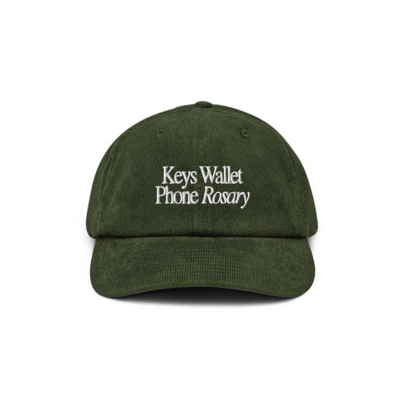 May include: A green corduroy baseball cap with white embroidery that reads "Keys Wallet Phone Rosary".