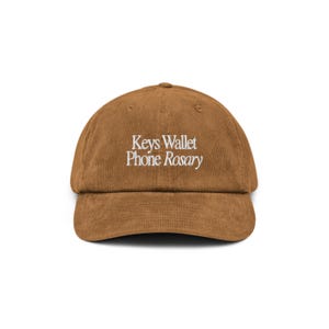May include: A brown corduroy baseball cap with white embroidery that reads "Keys Wallet Phone Rosary".