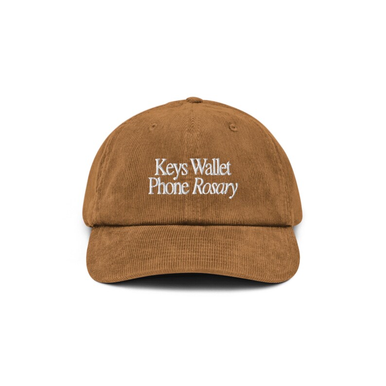 May include: A brown corduroy baseball cap with white embroidery that reads "Keys Wallet Phone Rosary".