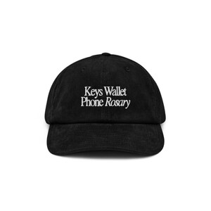 May include: A black corduroy baseball cap with white embroidered text that reads "Keys Wallet Phone Rosary".